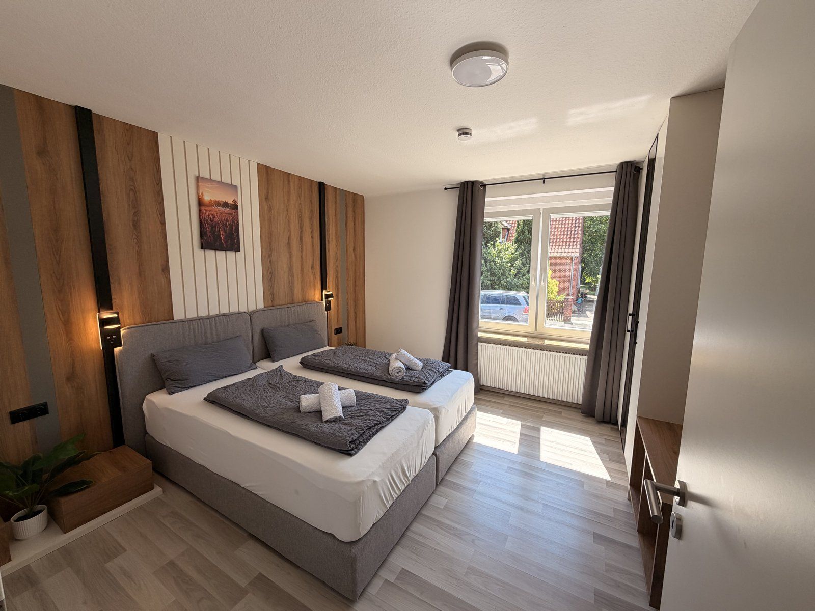 Helles Schlafzimmer mit Boxspringbetten und Holzwand